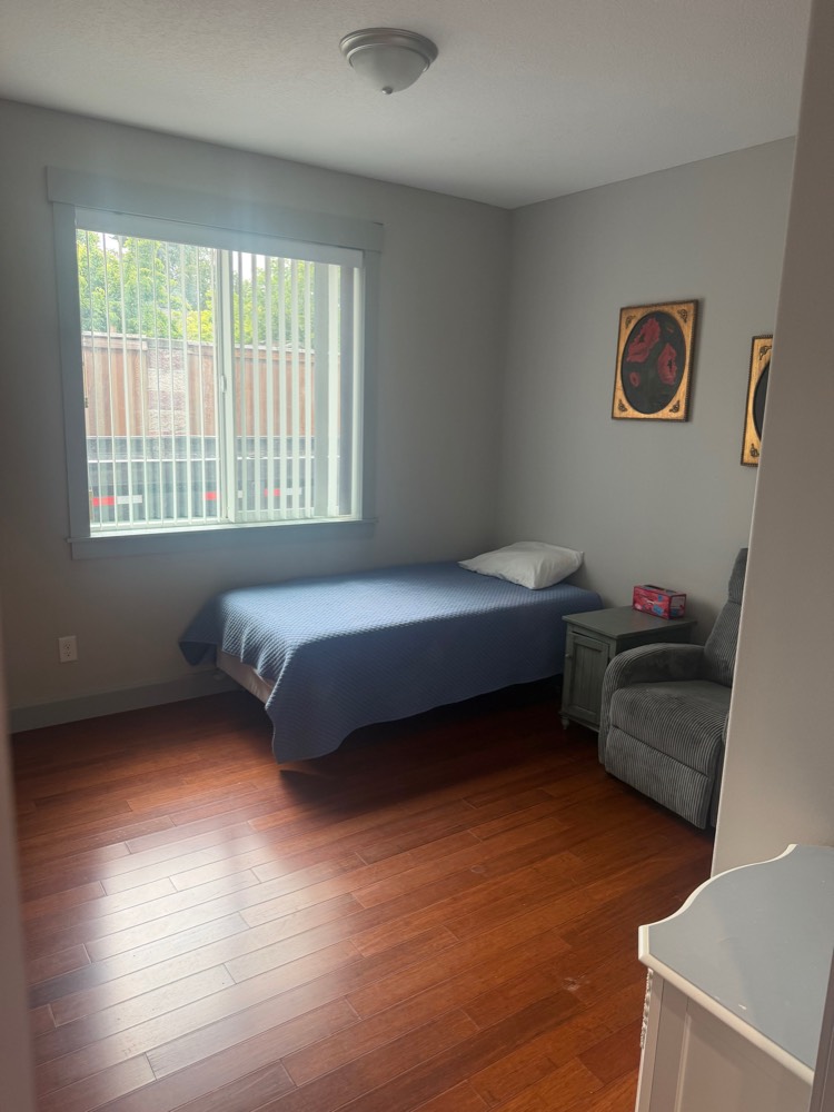 A private resident bedroom with natural light and hardwood floors
